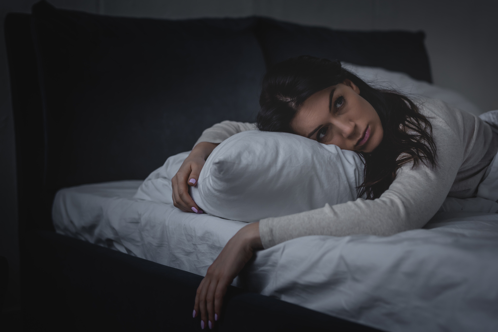 image of depressed woman laying on a bed