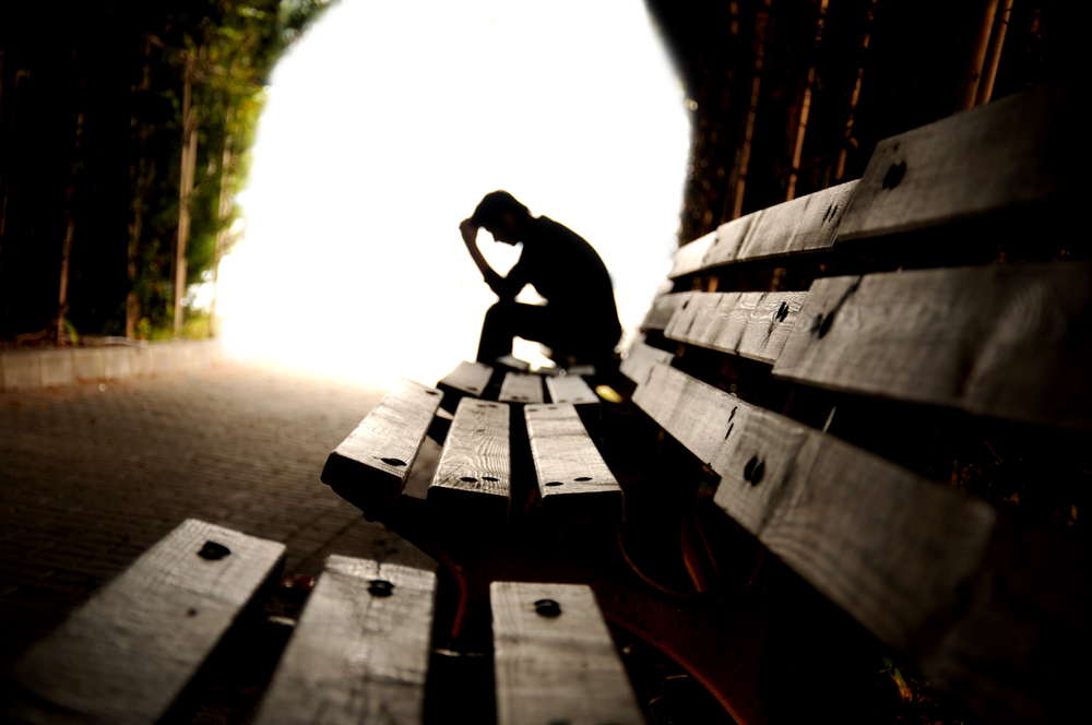 Depressed person sitting on a bench in a tunnel