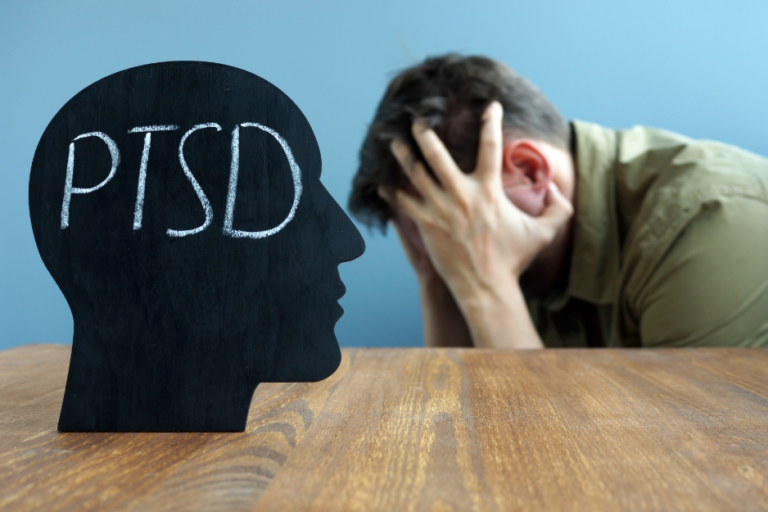 ptsd counseling services - man holding head next to a black silhouette that says PTSD
